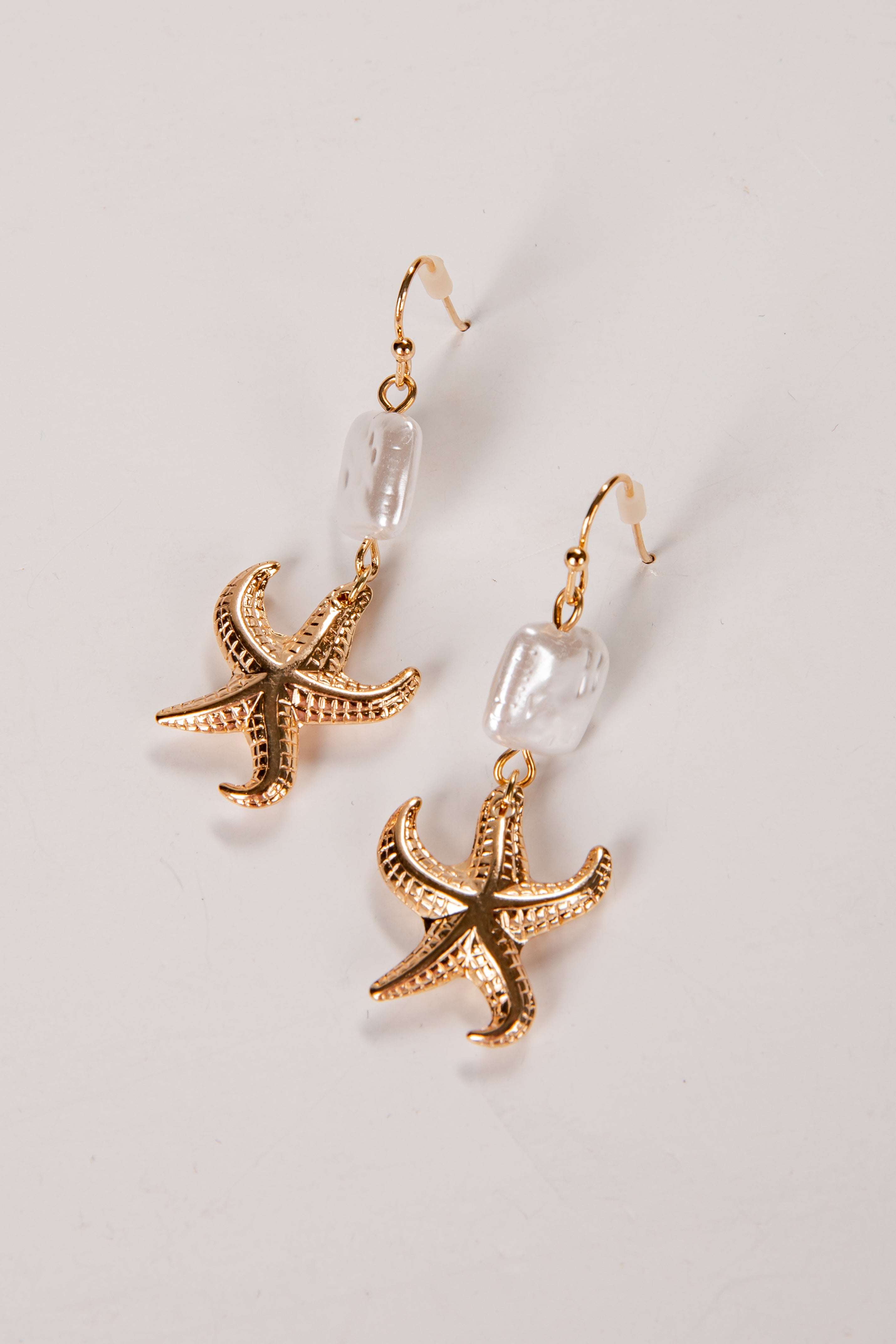 Gold starfish earrings on a light gray background