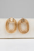 Gold hoop earrings on a white surface with a gray background