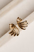 Gold wing-shaped earrings on a light beige surface