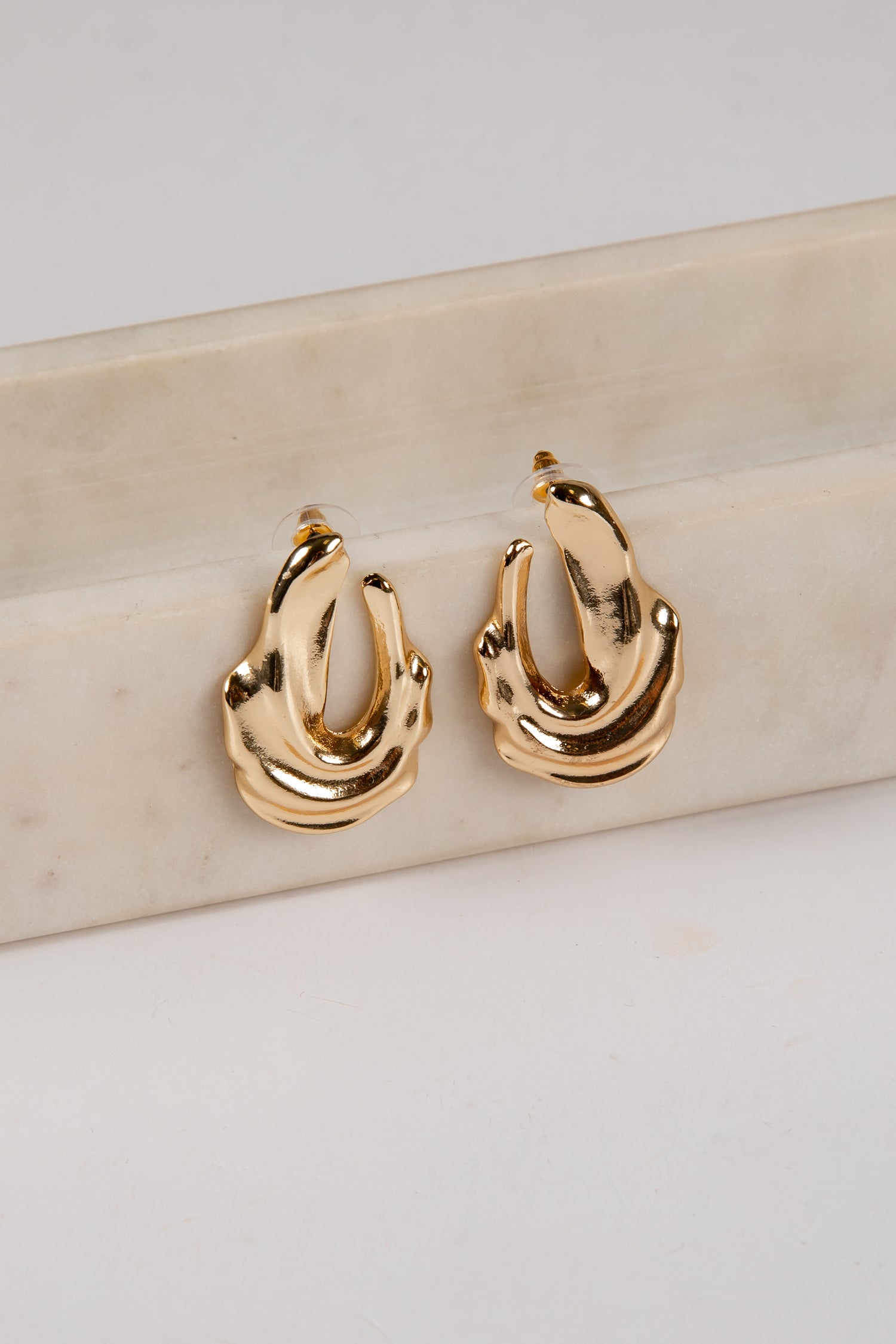 Gold hoop earrings on a light beige surface