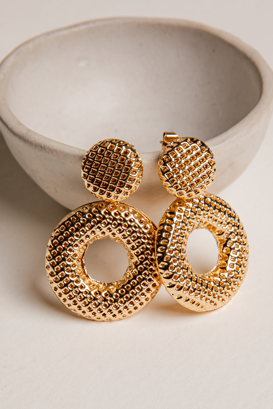 Gold earrings on a light background