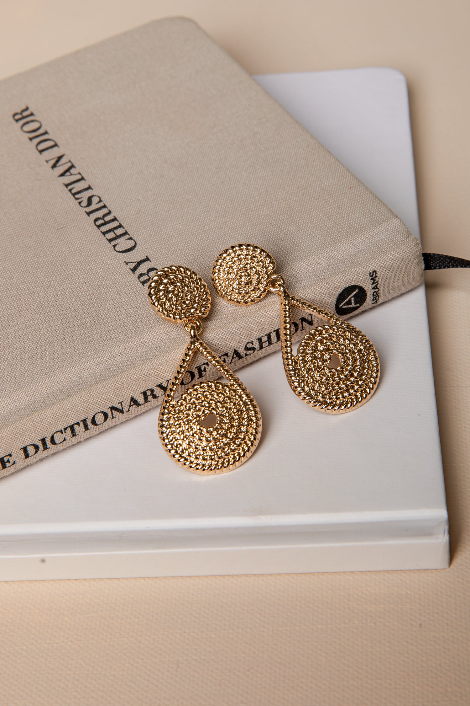 Gold earrings on a book with a beige cover