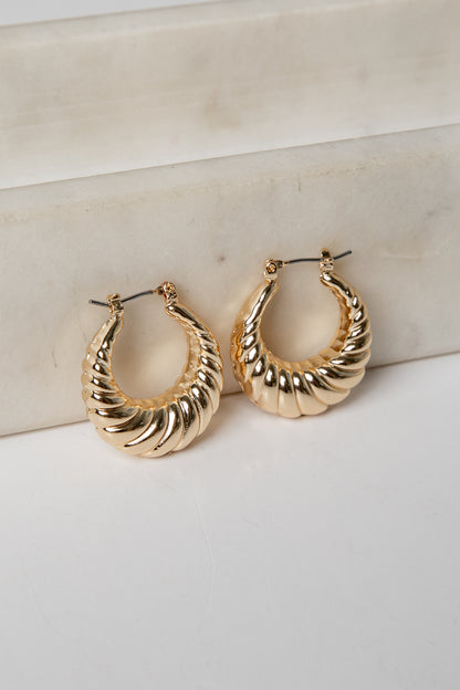 Gold hoop earrings on a marble surface