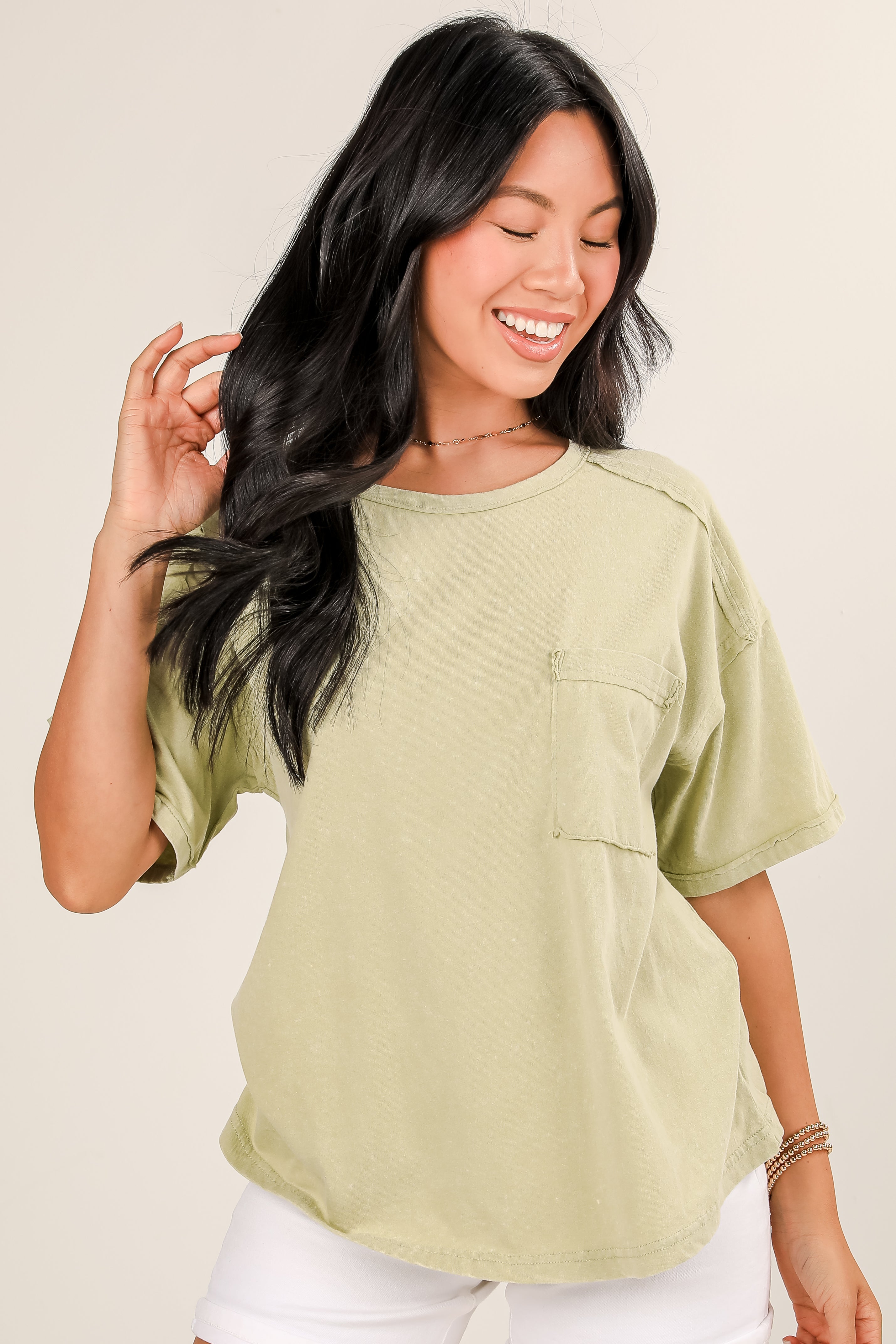Woman wearing a light green oversized t-shirt against a beige background