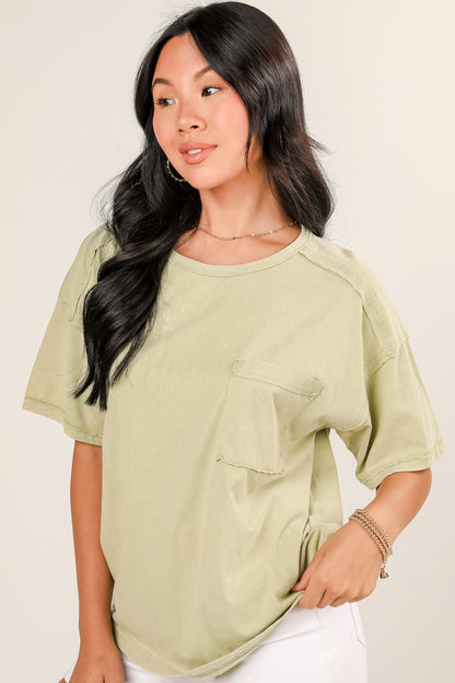 Woman wearing a light green oversized shirt with a pocket on a beige background