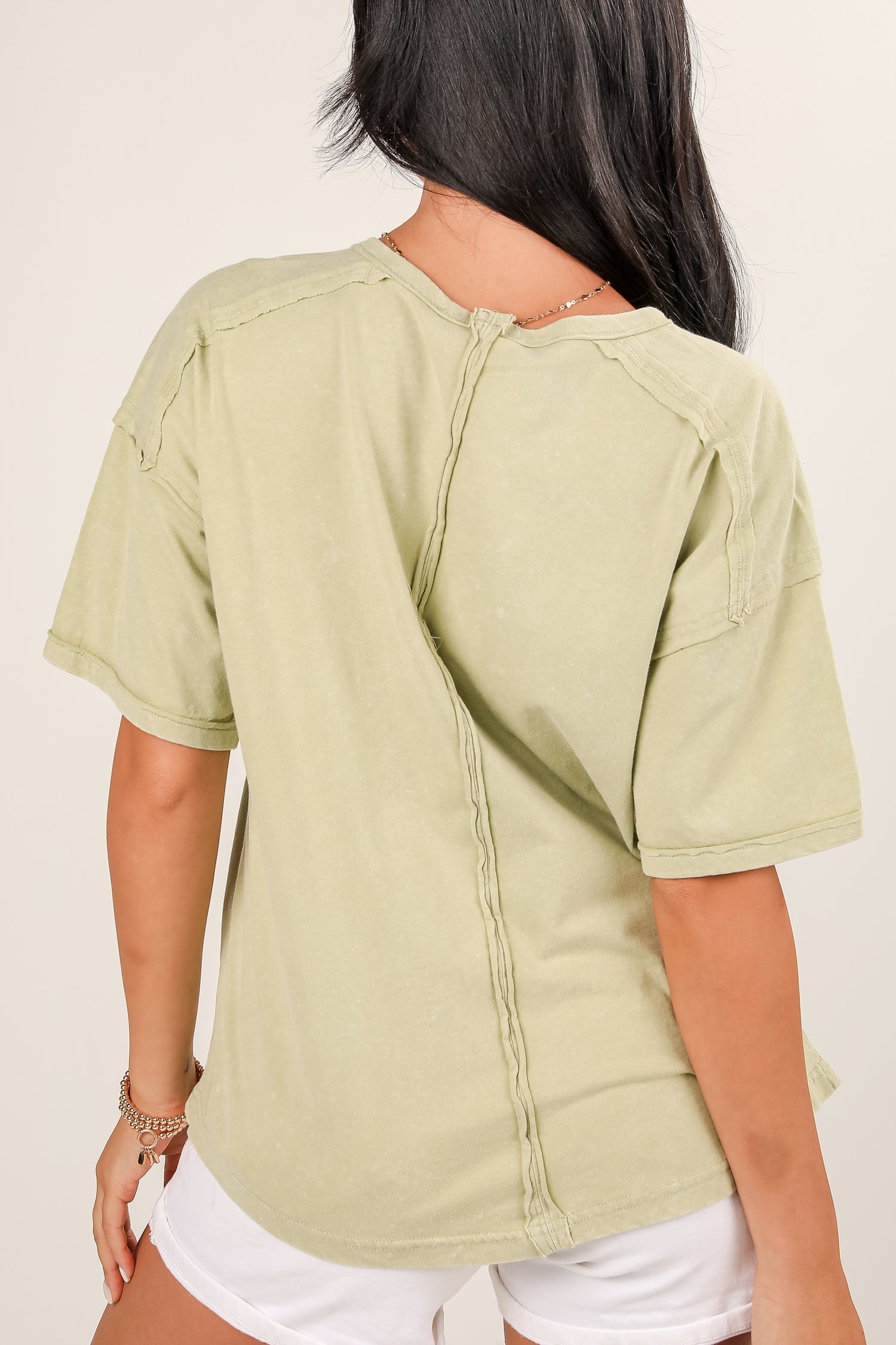 Person wearing a light green short-sleeve shirt with a plain background