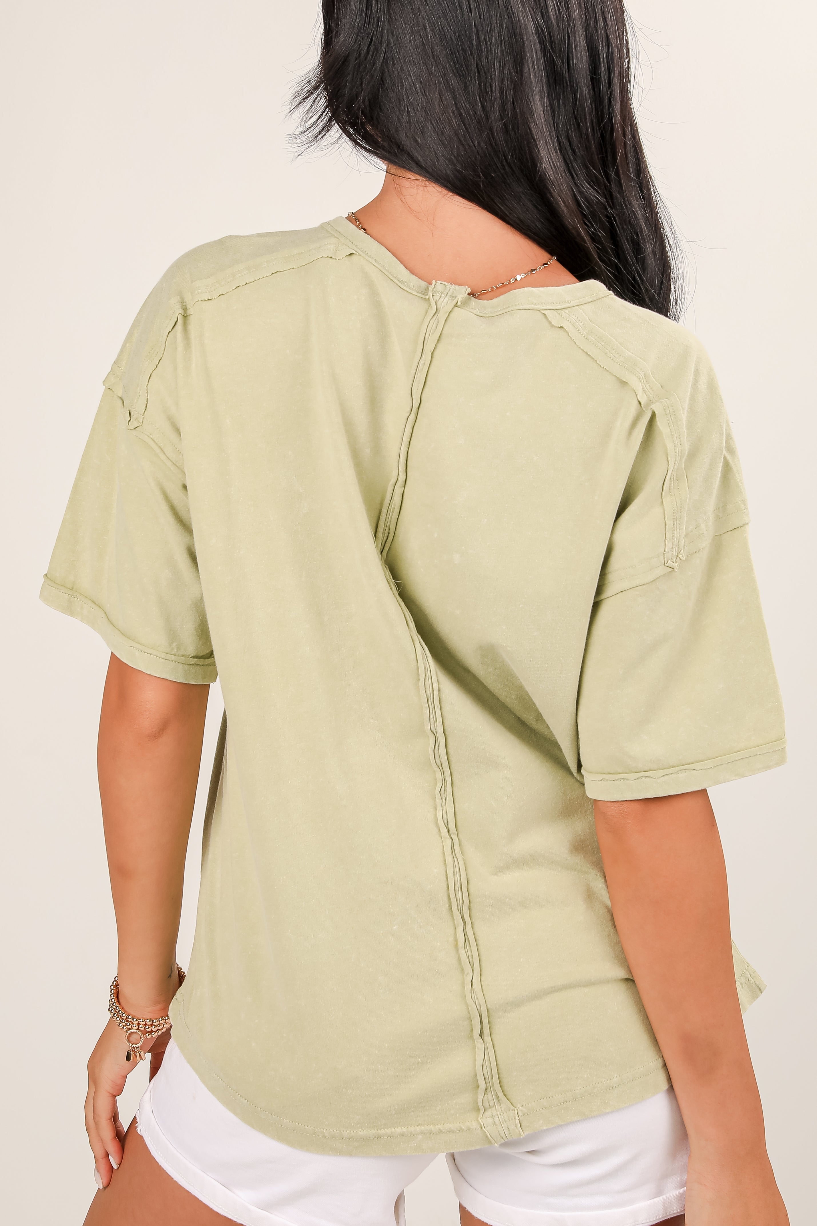 Person wearing a light green short-sleeve shirt with a plain background