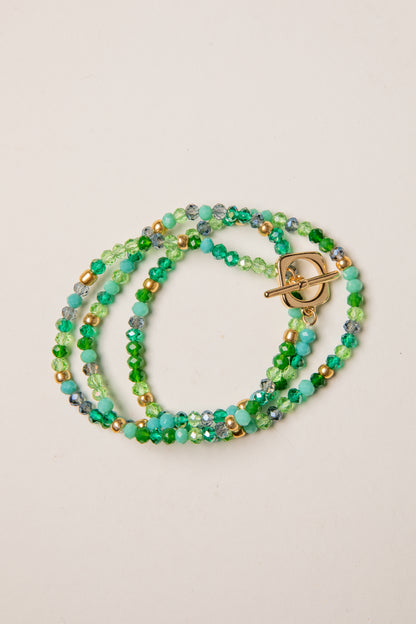 Multistrand beaded bracelet with a gold clasp on a beige background