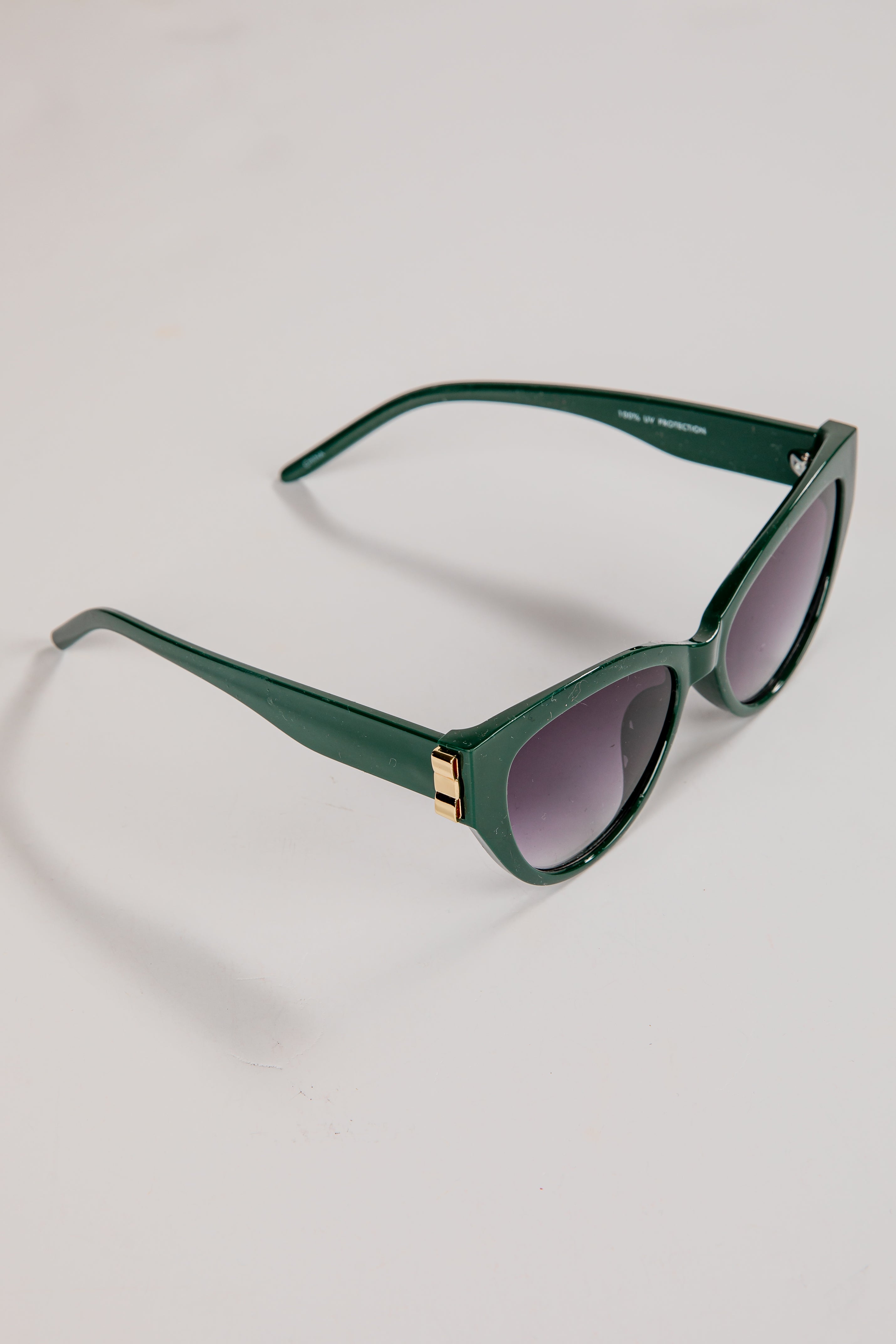 Green sunglasses with dark lenses on a light gray background