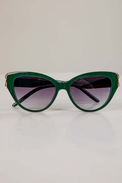Green cat-eye sunglasses with gold accents on a light gray background