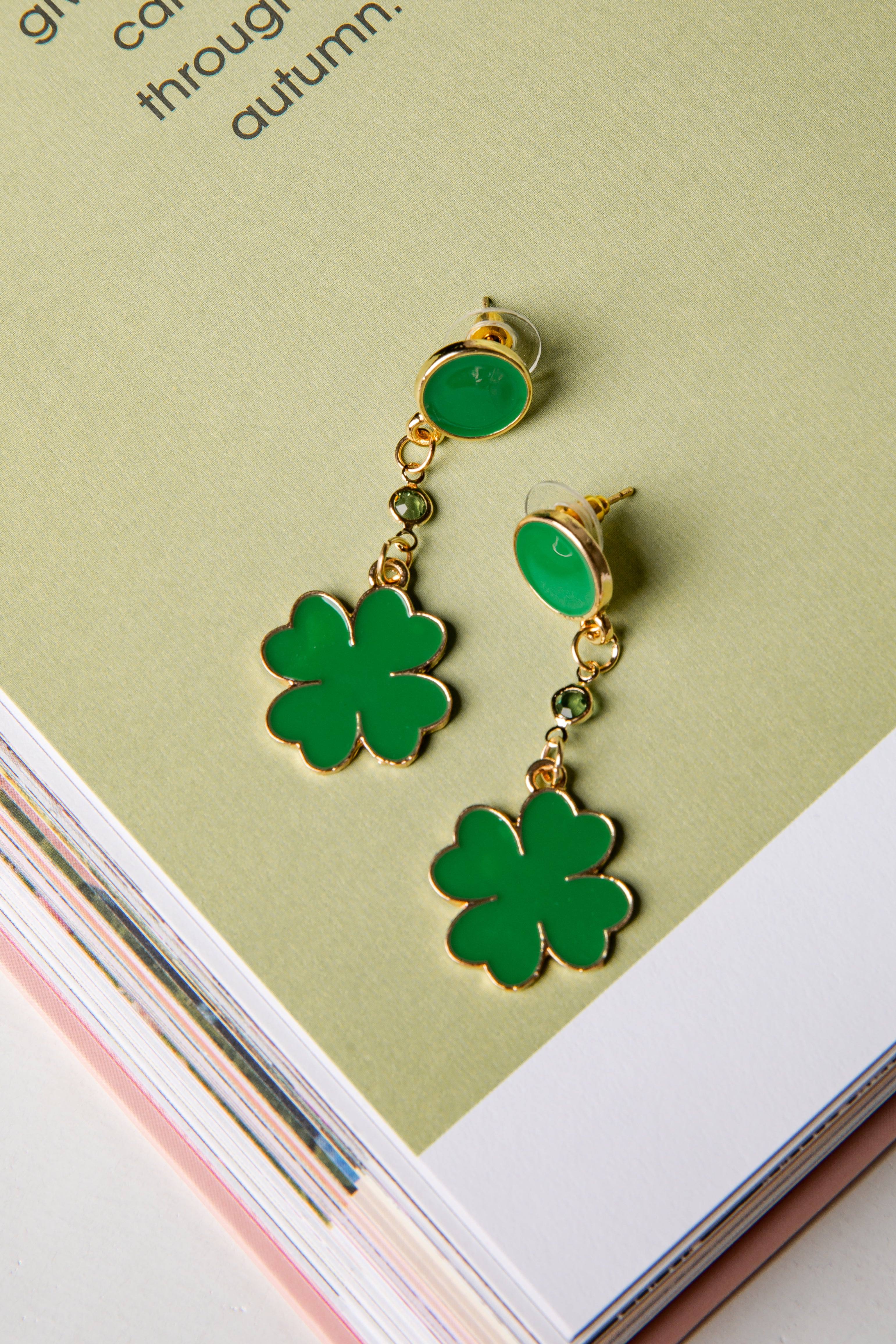 Green four-leaf clover earrings on a light green background