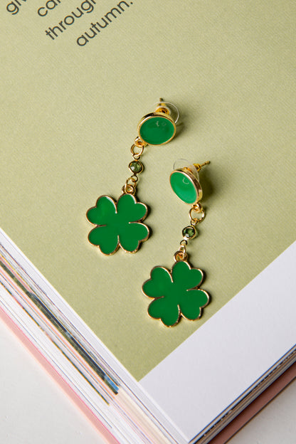 Green four-leaf clover earrings on a light green background