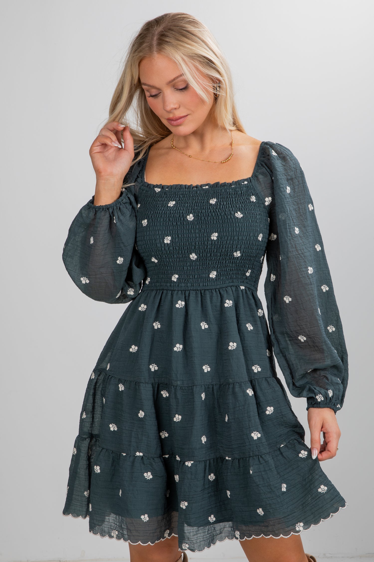 Woman wearing a dark green dress with floral pattern on a plain background