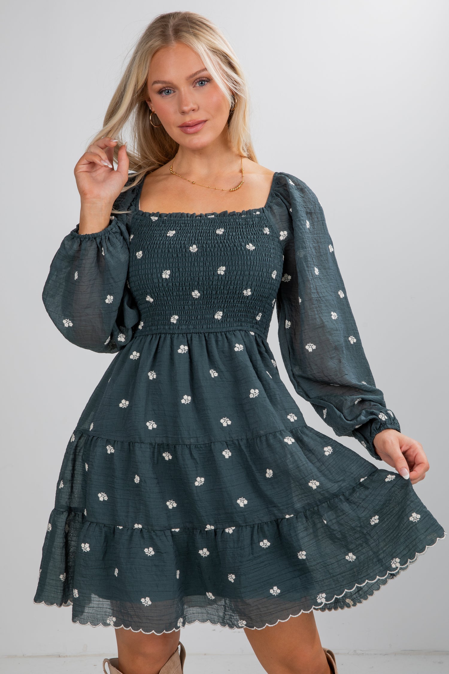 Woman wearing a dark green dress with floral pattern on a gray background