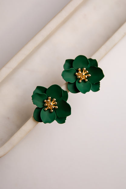 Green flower-shaped earrings with gold centers on a light background