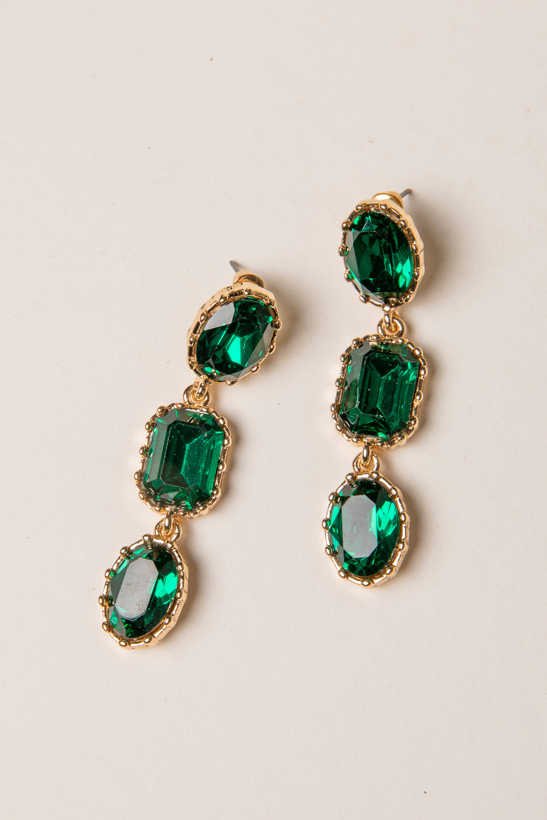 Green gemstone earrings with gold accents on a light background