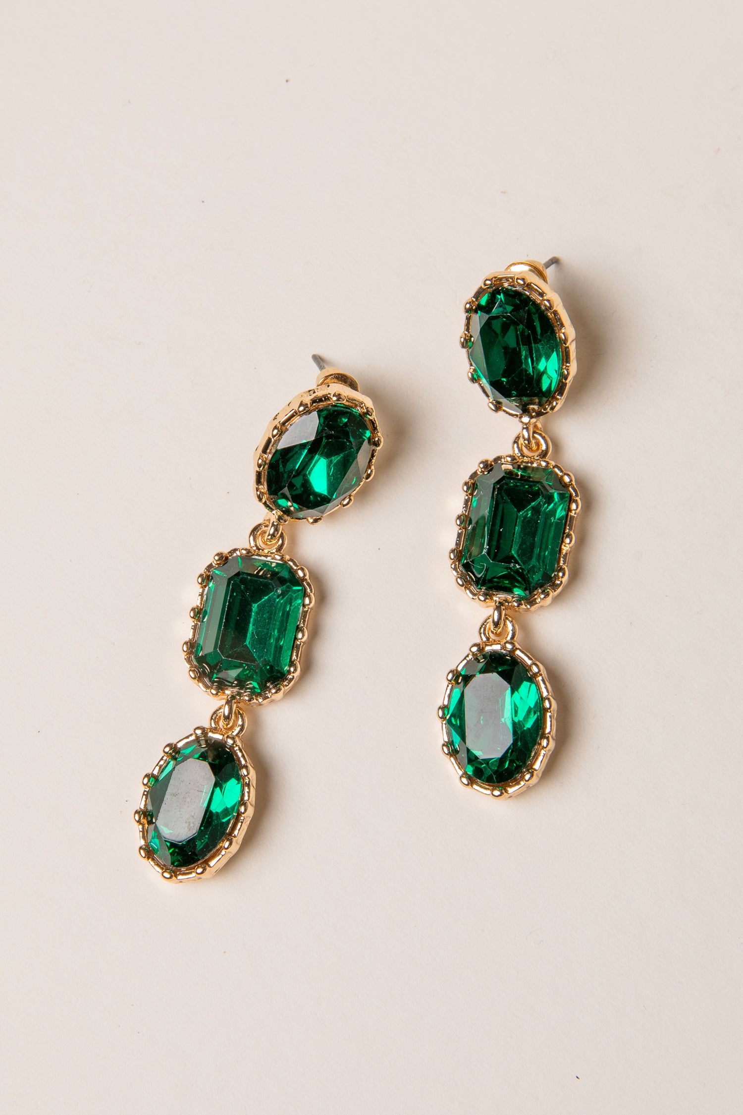 Green gemstone earrings with gold accents on a light background