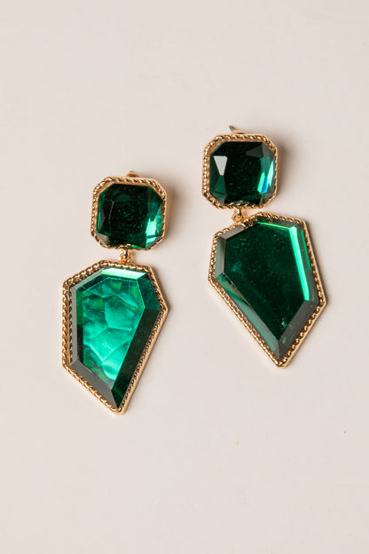 Green gemstone earrings with gold accents on a beige background