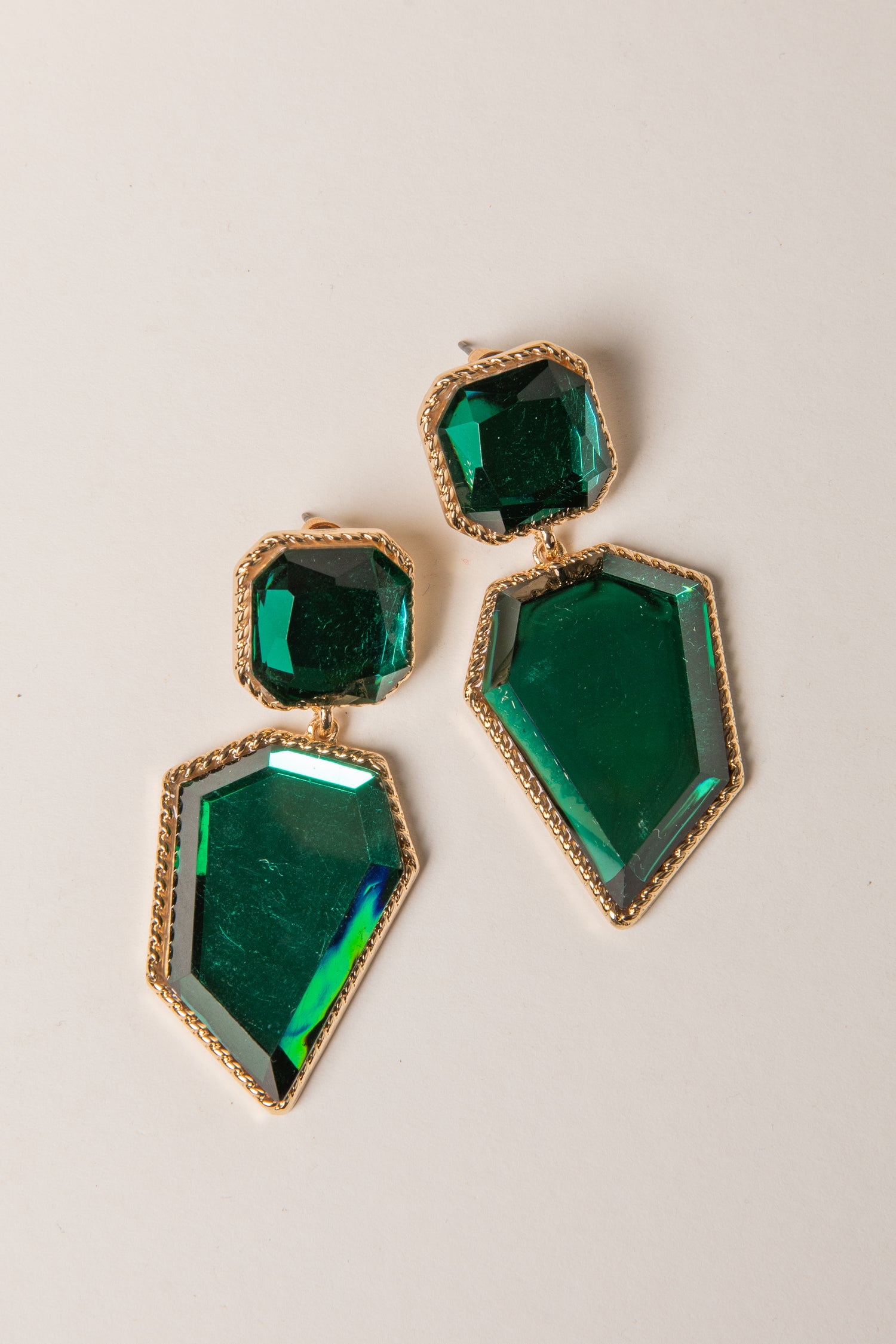 Green gemstone earrings with gold accents on a light gray background