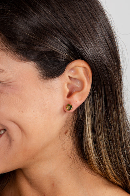 Close-up of a person wearing a green earring with a neutral background