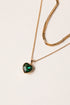 Gold necklace with a heart-shaped green gemstone pendant on a light background