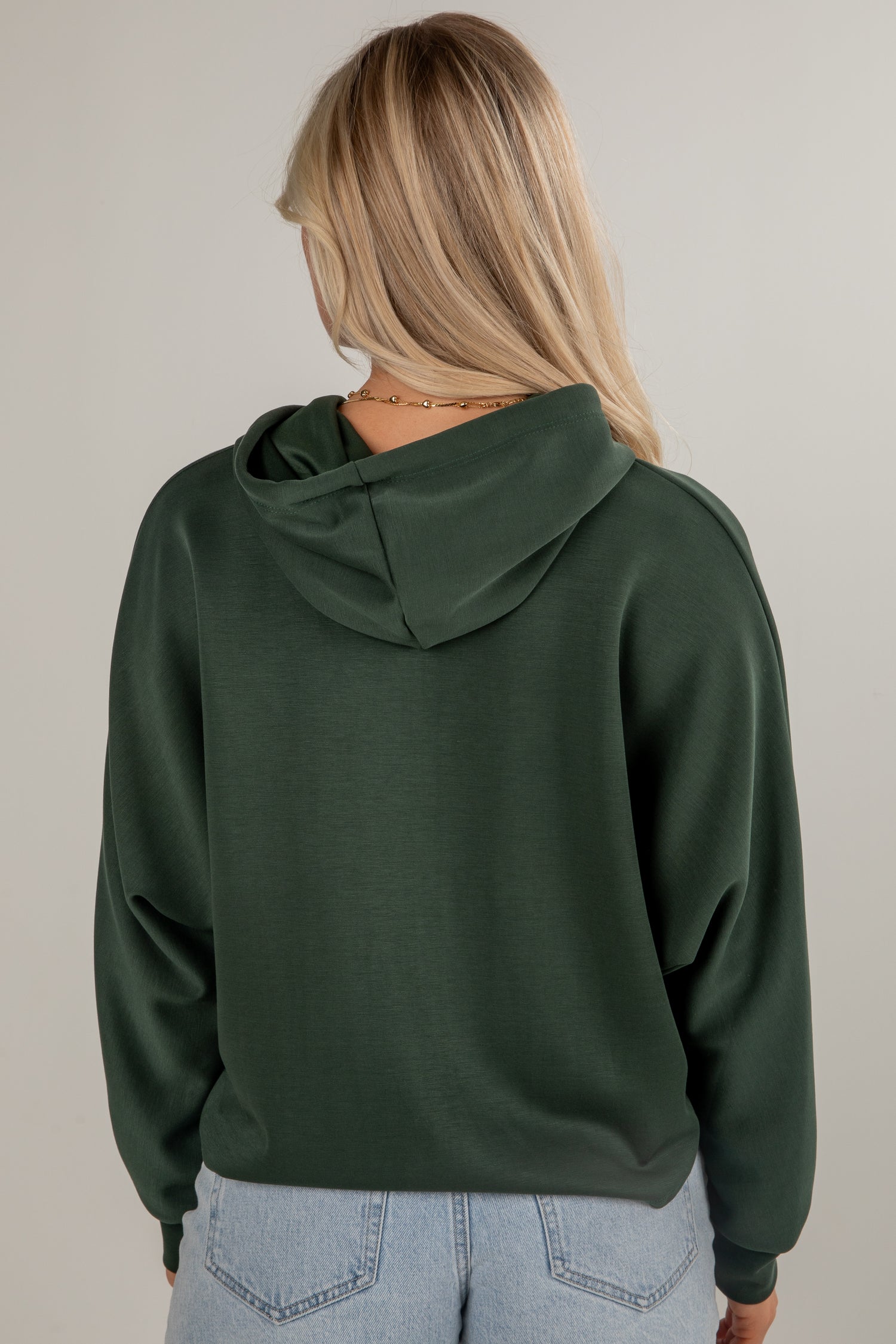 Person wearing a green hoodie from behind on a plain background