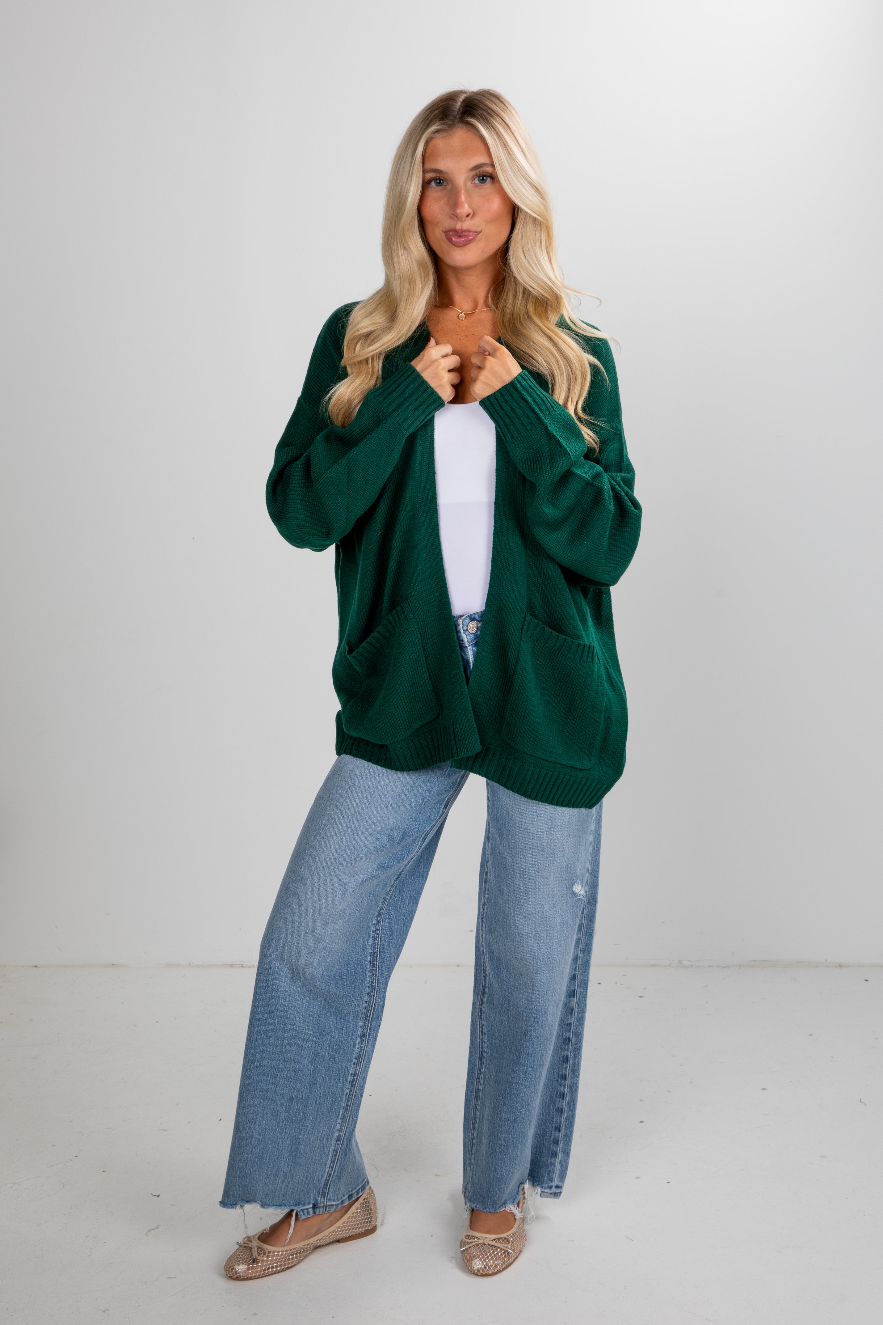Woman wearing a green sweater and blue jeans against a white background