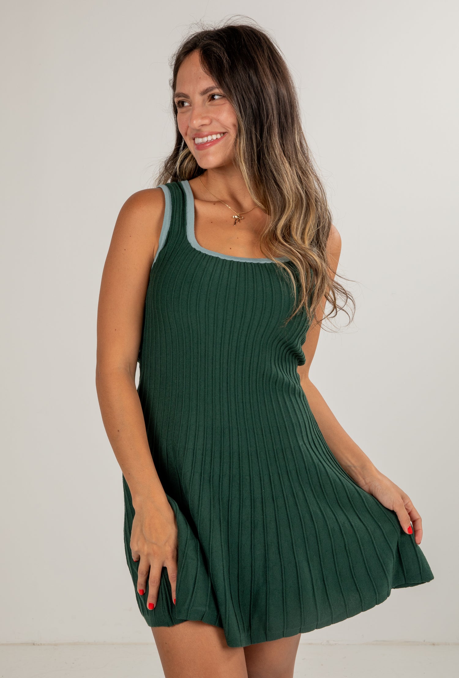 Woman wearing a green ribbed dress against a plain background
