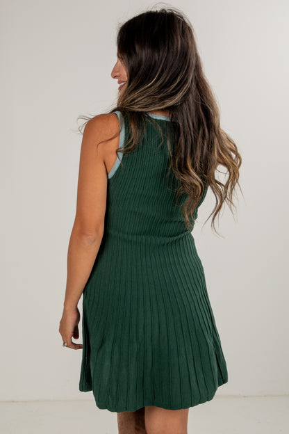 Woman wearing a green ribbed dress against a white background