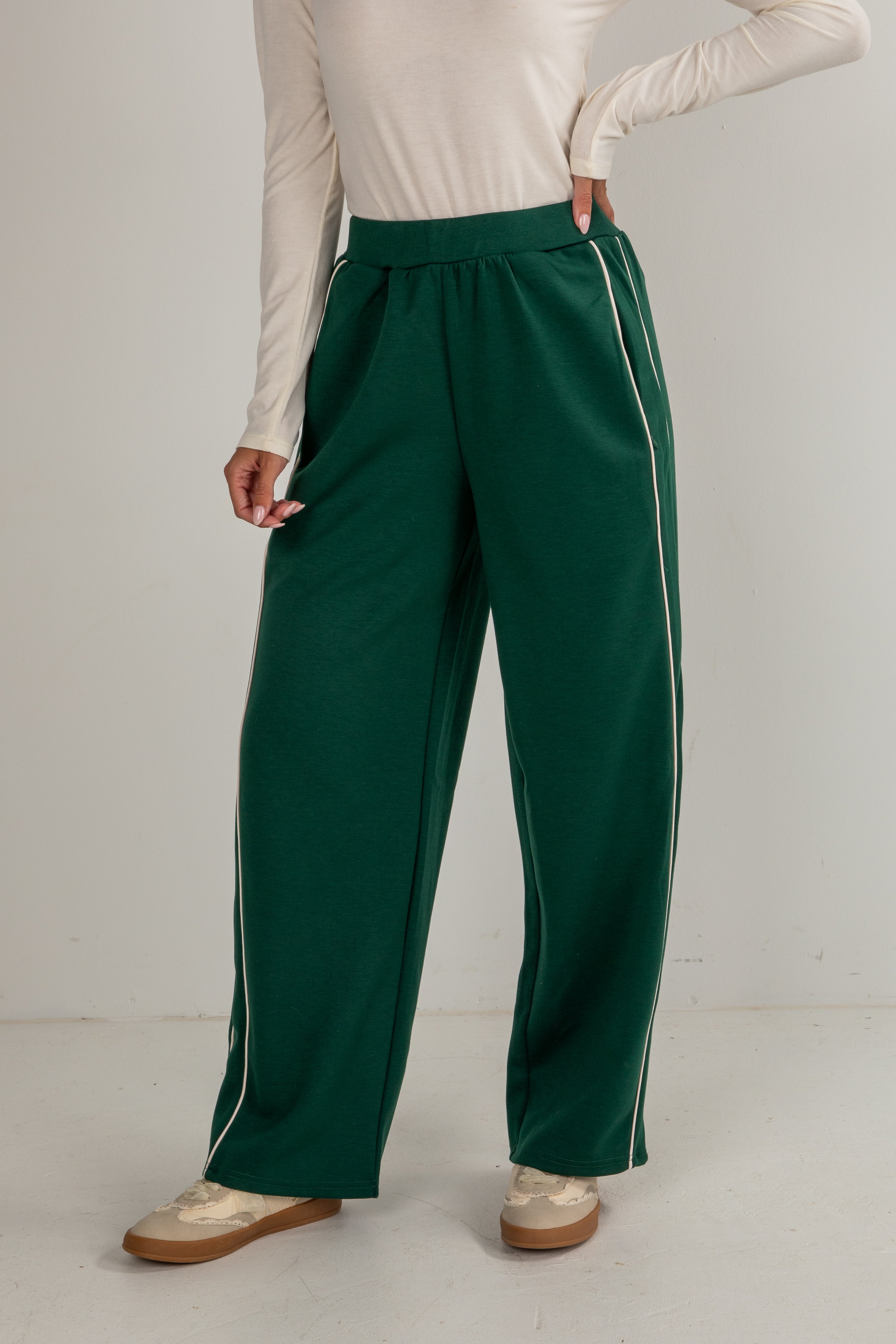 Person wearing green pants with white stripes on a plain background