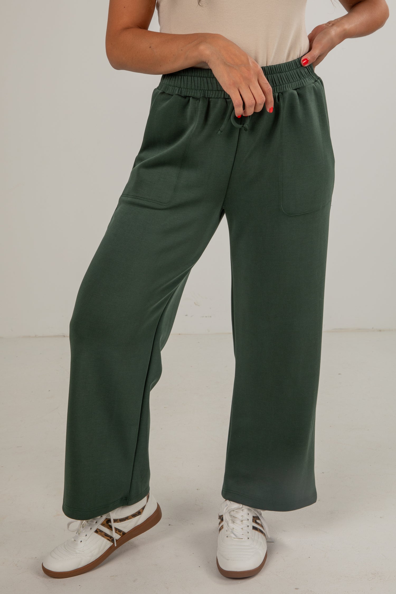 Person wearing green wide-leg pants with a plain background