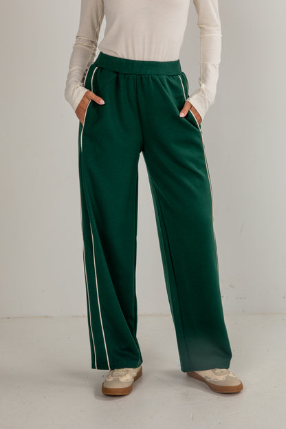 Person wearing green pants with white stripes on a plain background