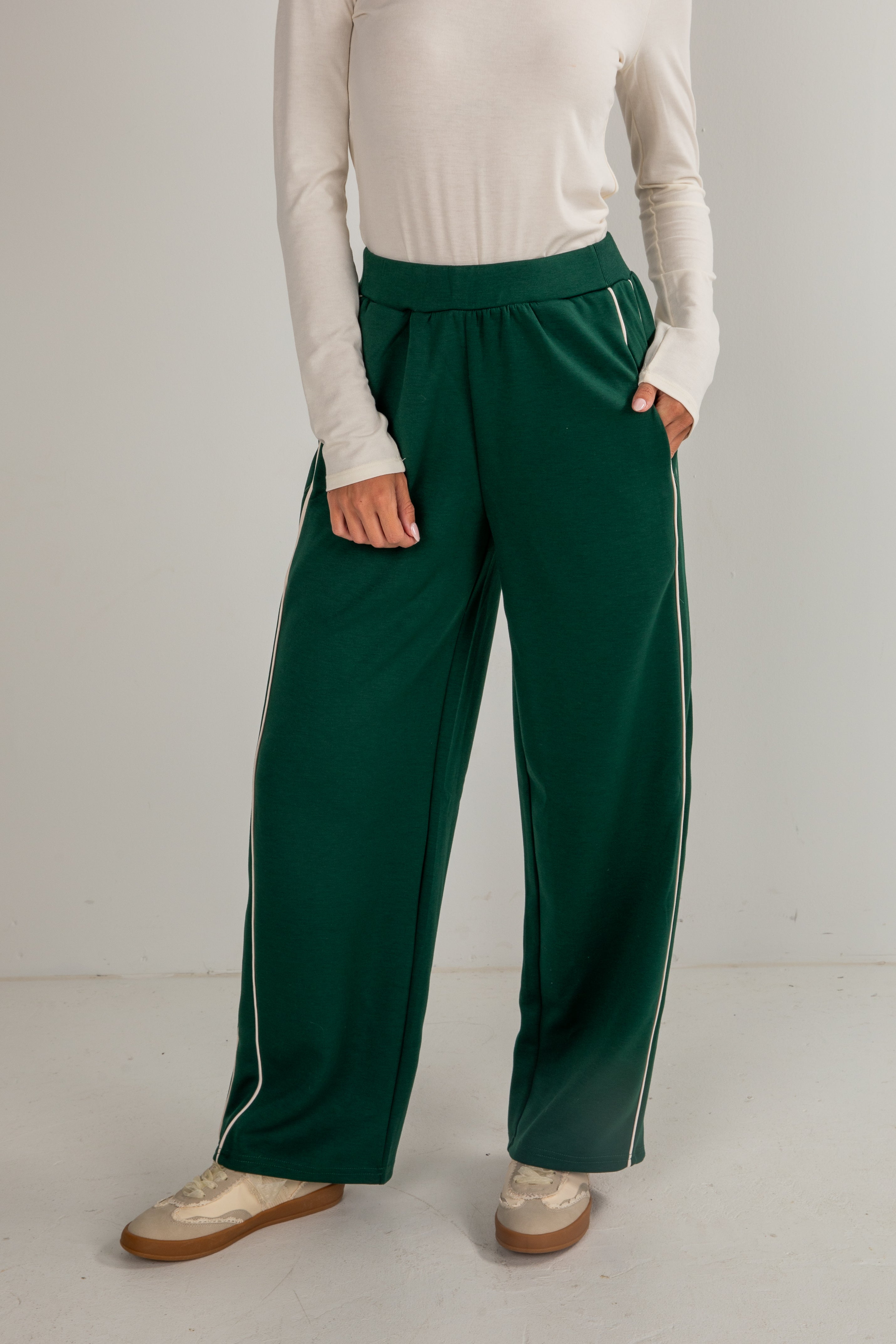 Person wearing green pants with white stripes on a plain background