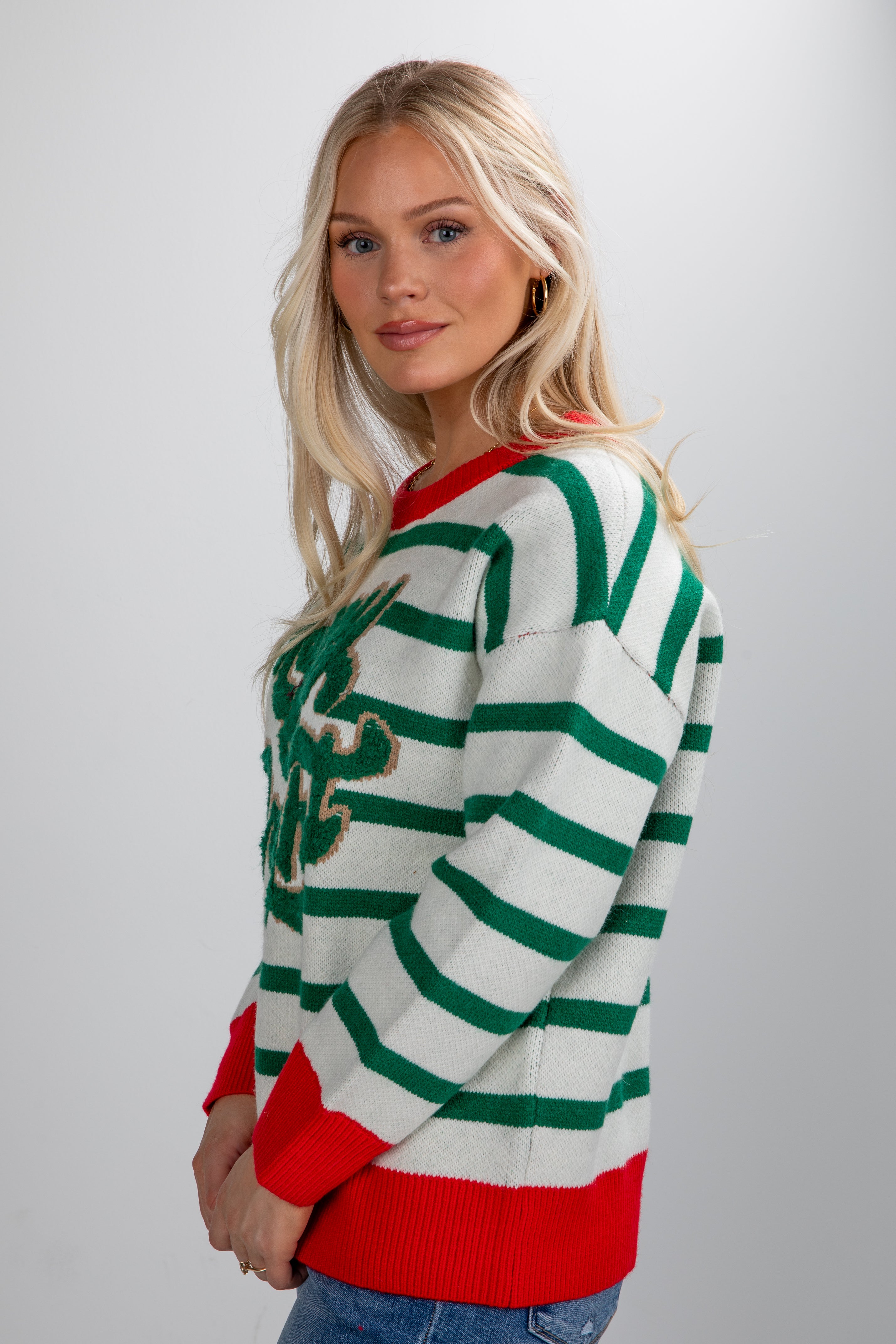Woman wearing a green and red striped sweater with a white background