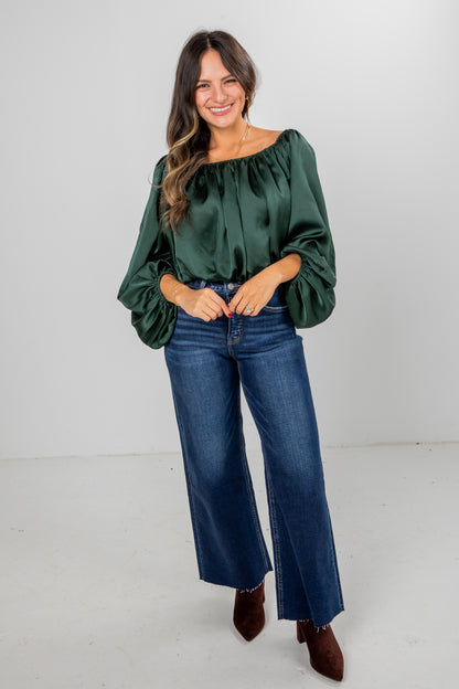 Woman wearing a green blouse and blue jeans on a white background