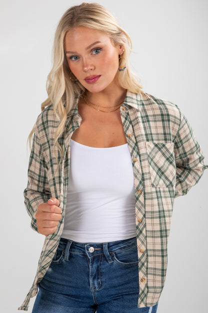 Woman wearing a plaid shirt over a white tank top and jeans on a plain background