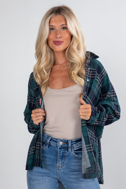 Woman wearing a plaid shirt over a beige top and jeans on a white background