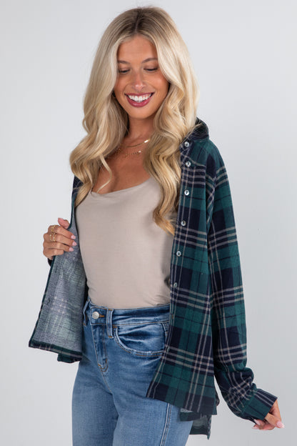 Woman wearing a plaid shirt over a beige top and jeans on a white background