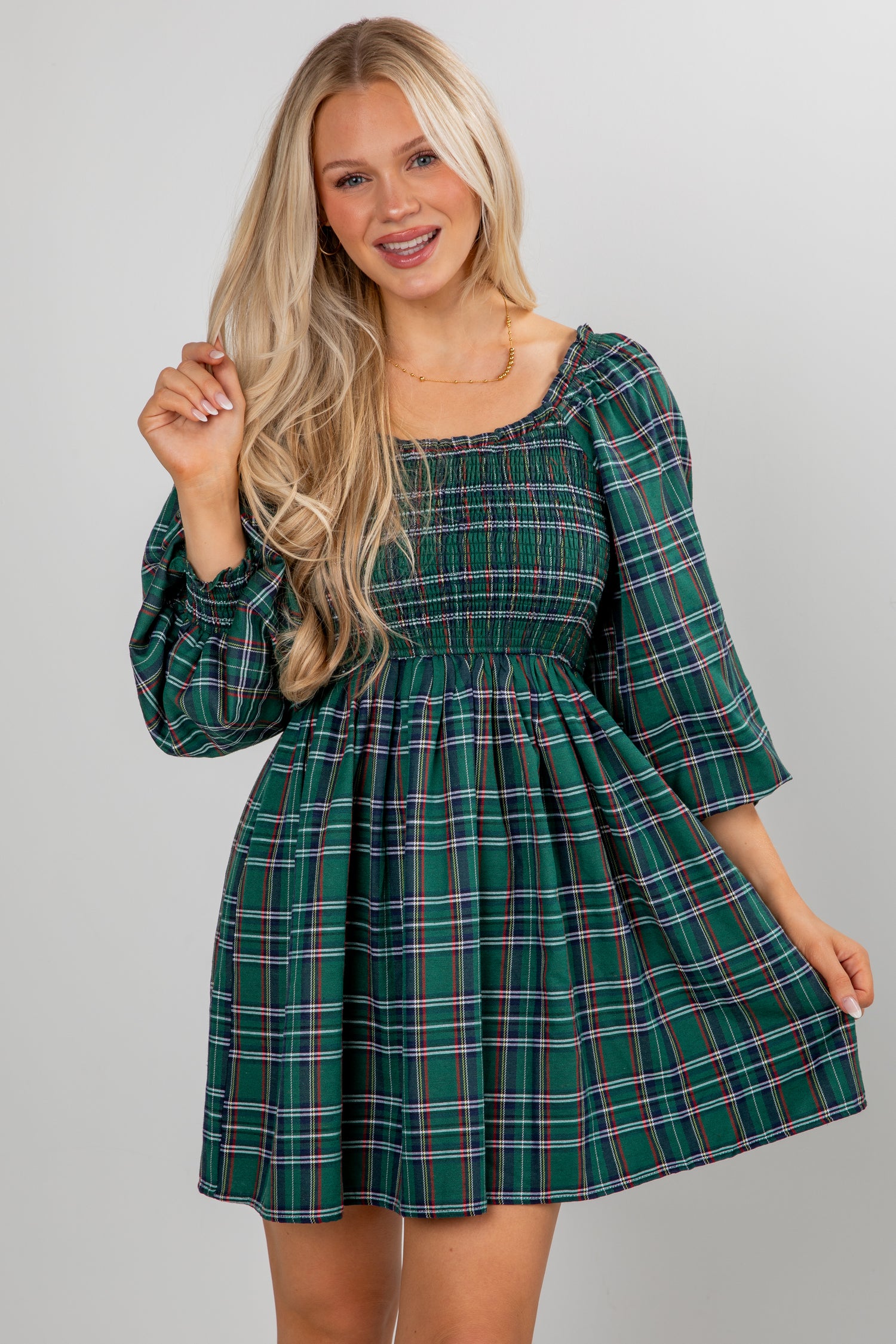 Woman wearing a green plaid dress against a plain background