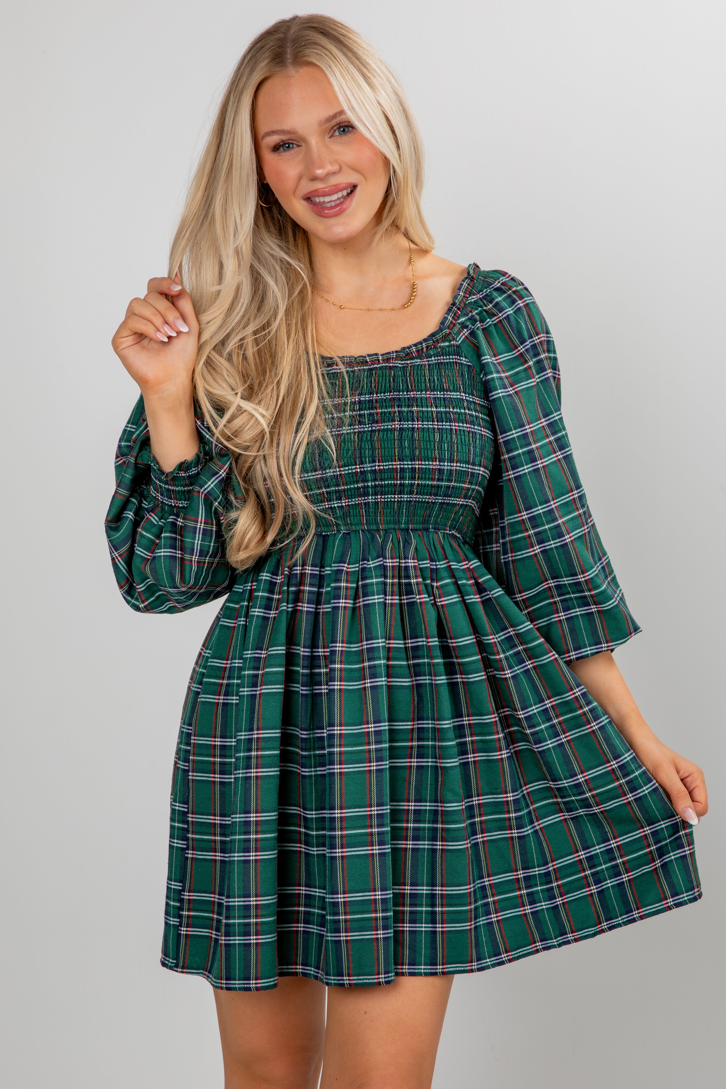 Woman wearing a green plaid dress against a plain background