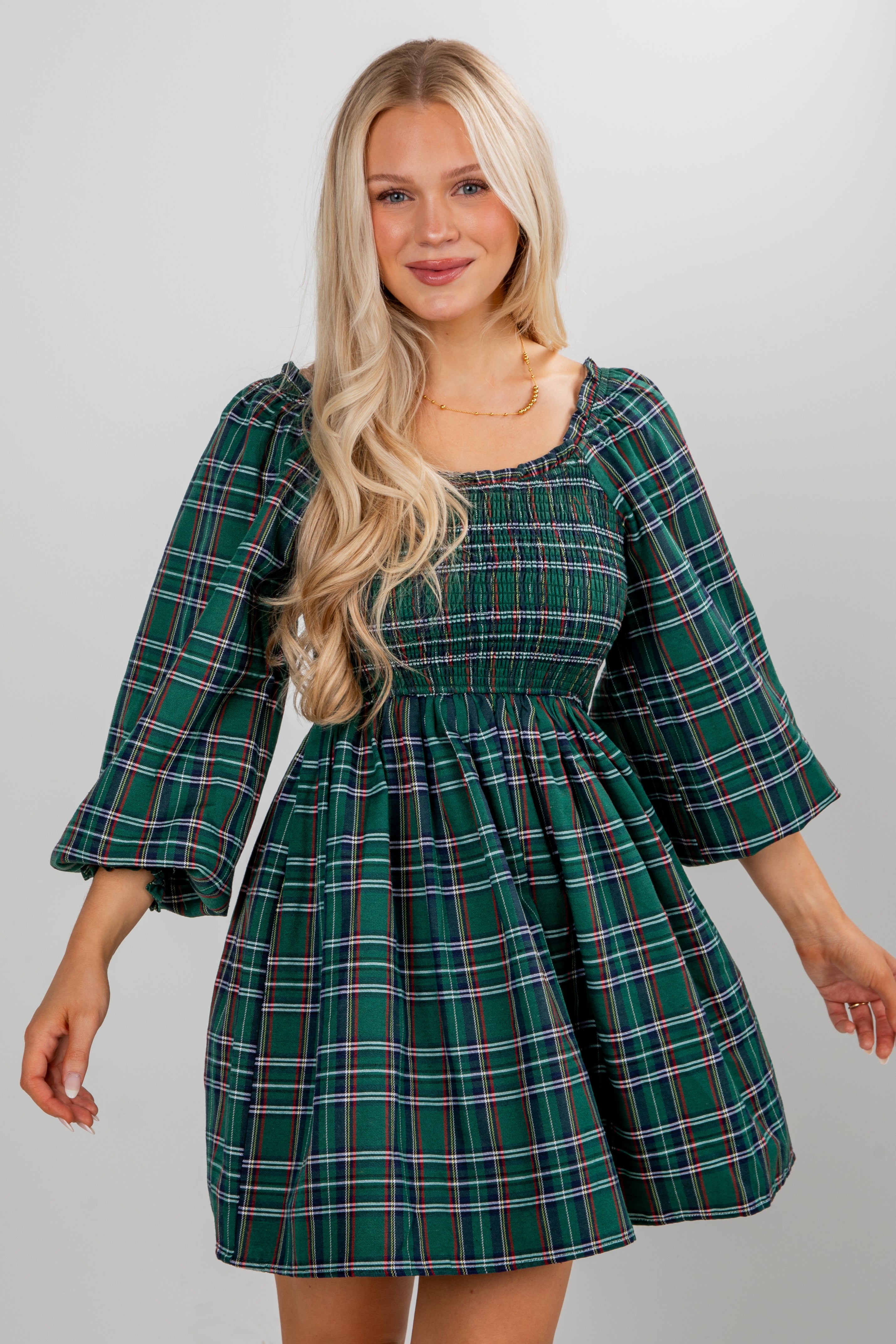 Woman wearing a green plaid dress against a plain background