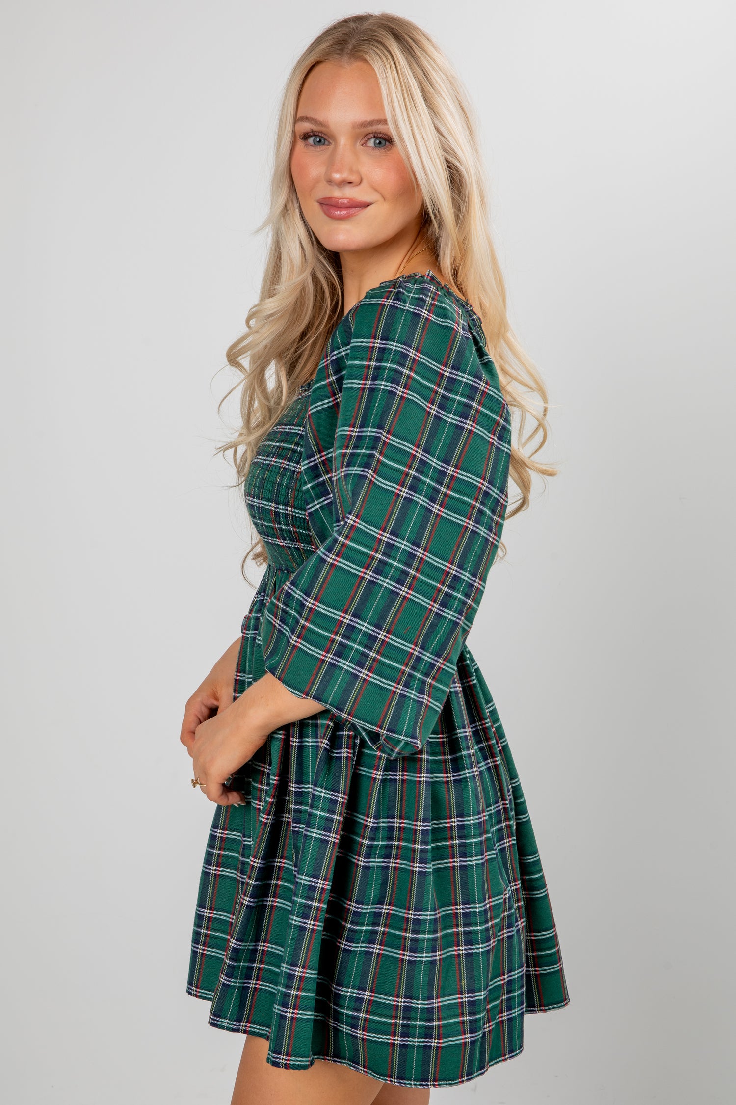 Woman wearing a green plaid dress against a plain background