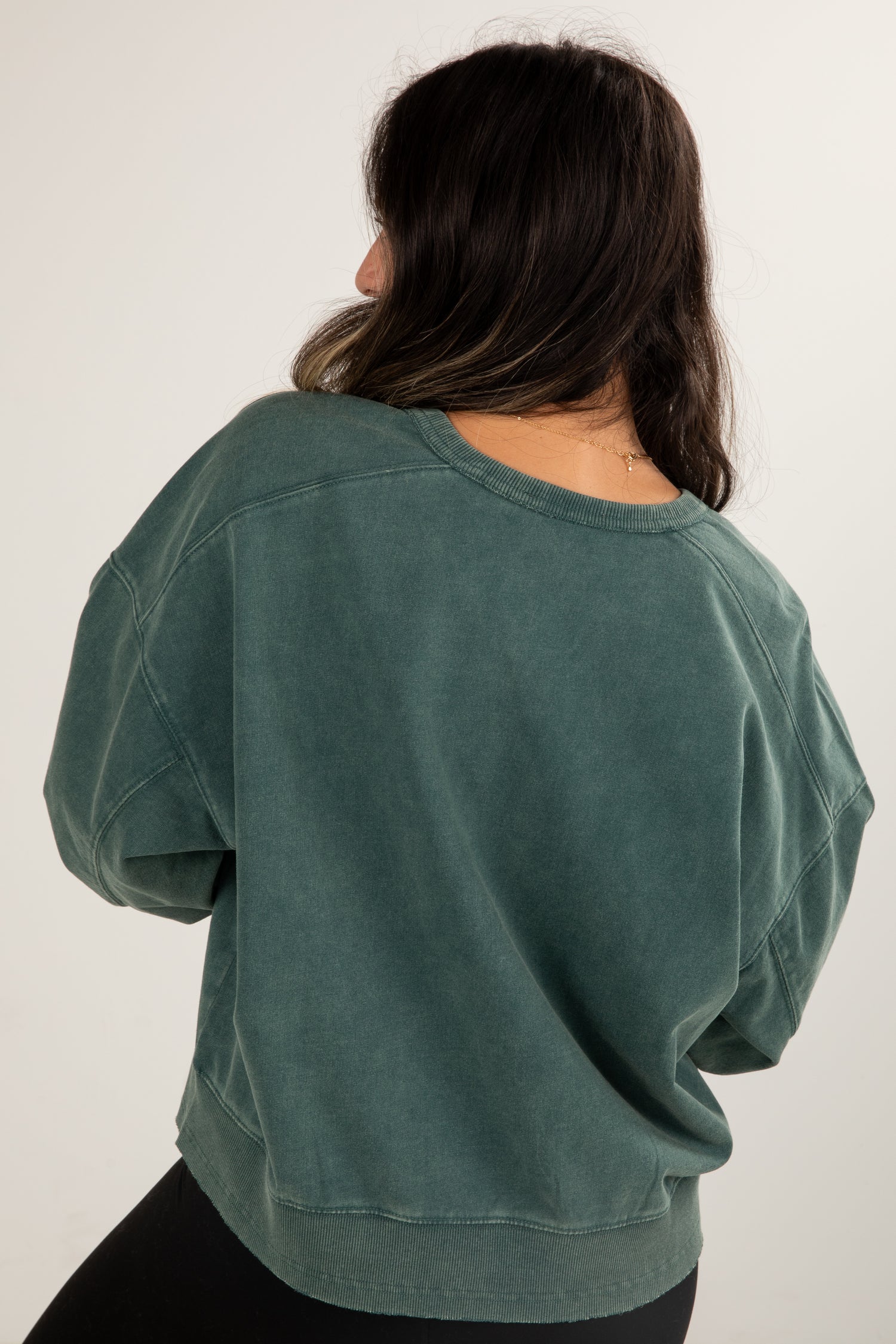 Person wearing a green oversized sweater on a white background