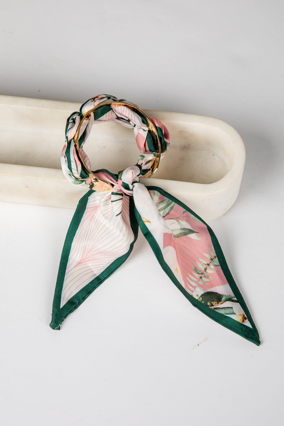 Floral scarf tied around a cylindrical object on a white background