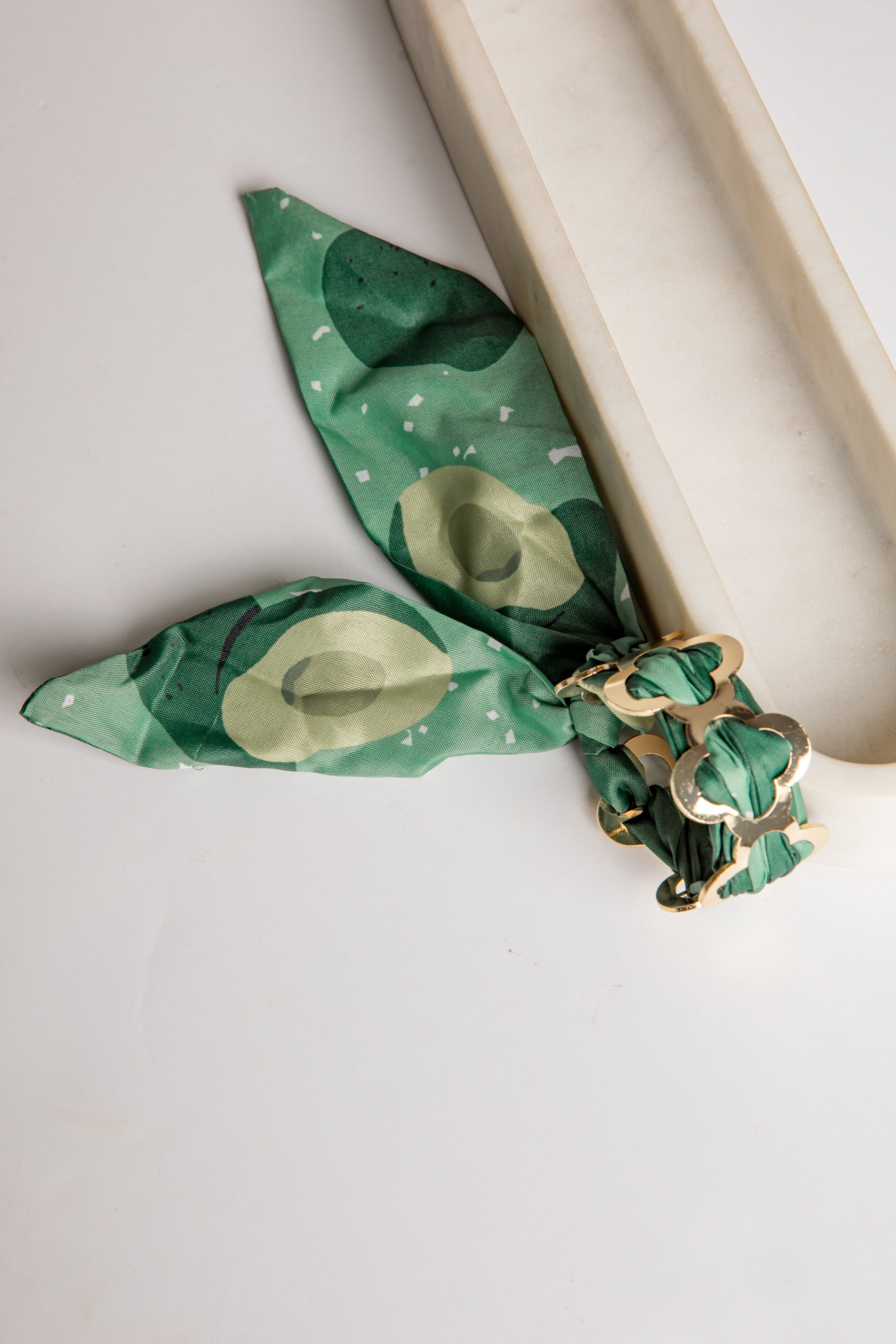 Green bracelet with gold accents on a white background