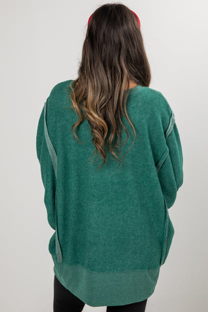 Person wearing a green sweater with gray accents on a plain background