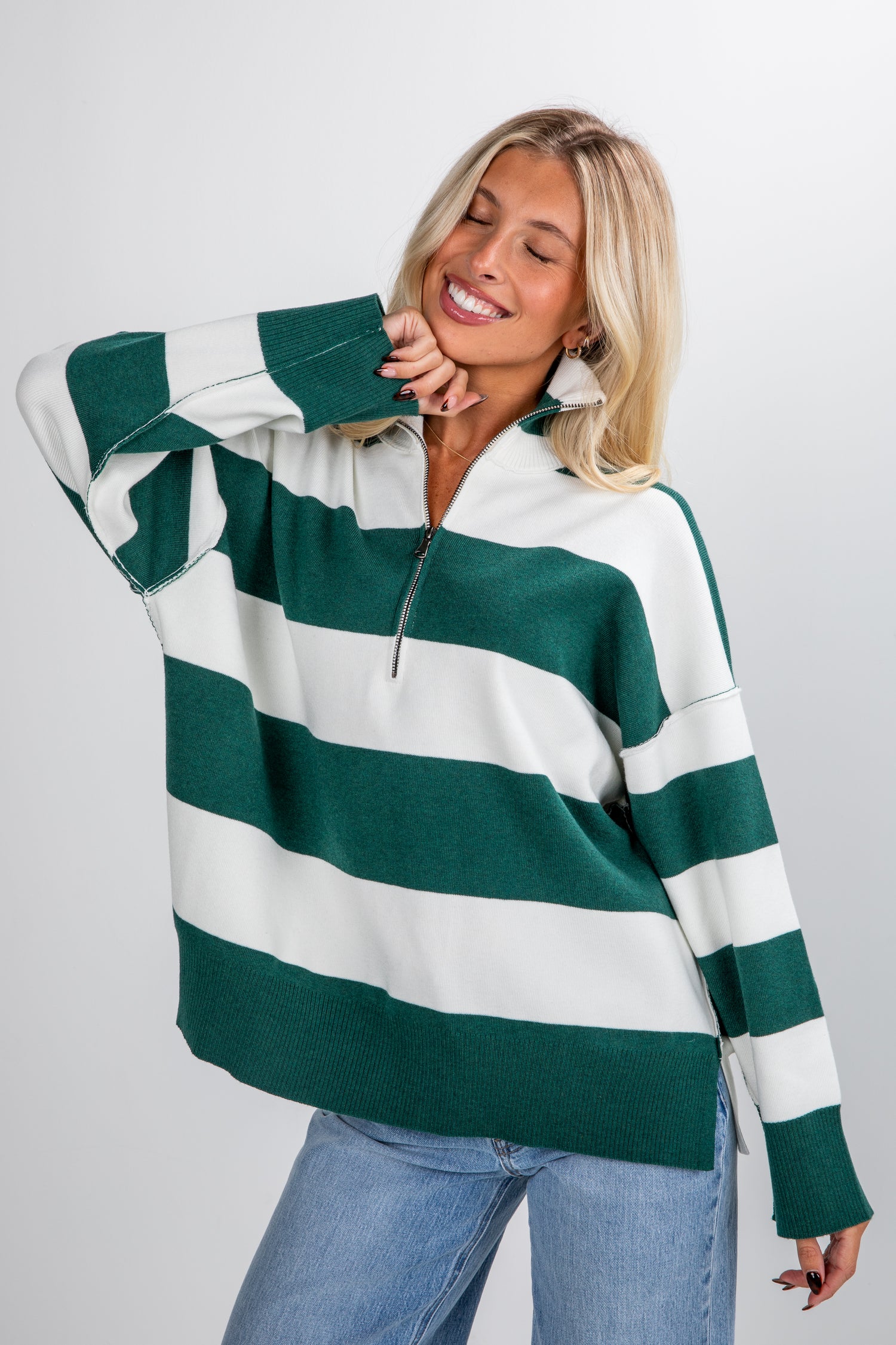 Woman wearing a green and white striped sweater on a plain background