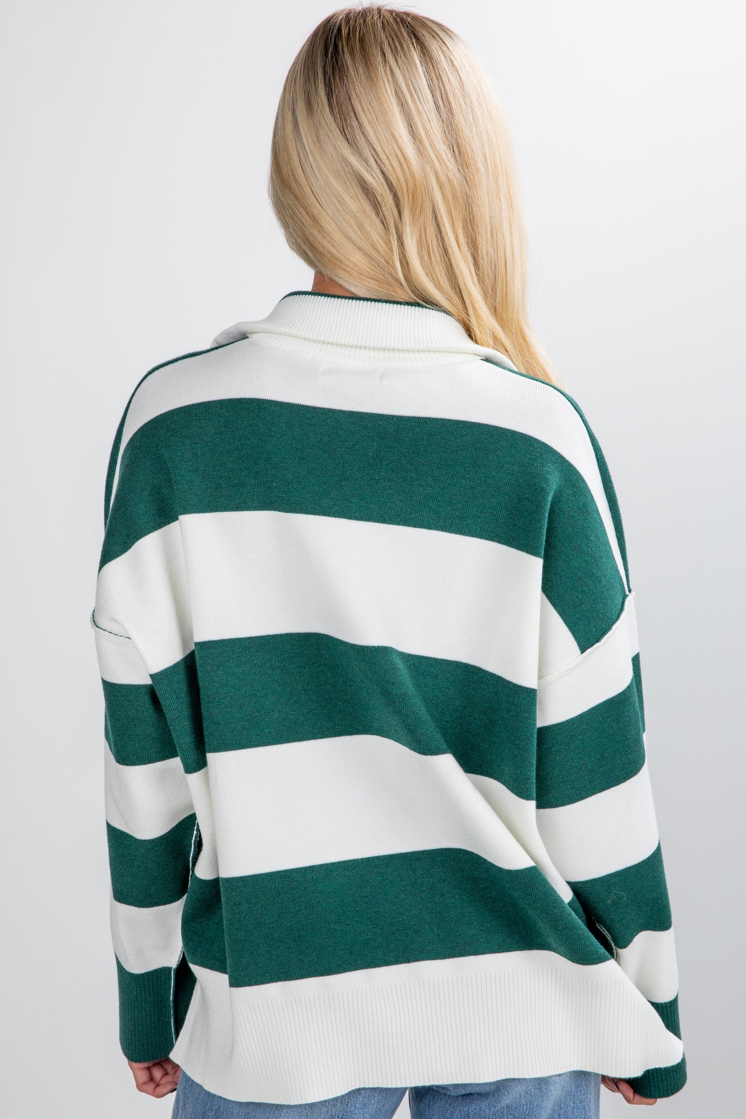 Person wearing a green and white striped sweater on a plain background