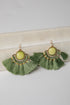 Green tassel earrings with gold accents on a light surface