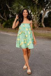 Woman wearing a green and white striped dress with lemon pattern outdoors.